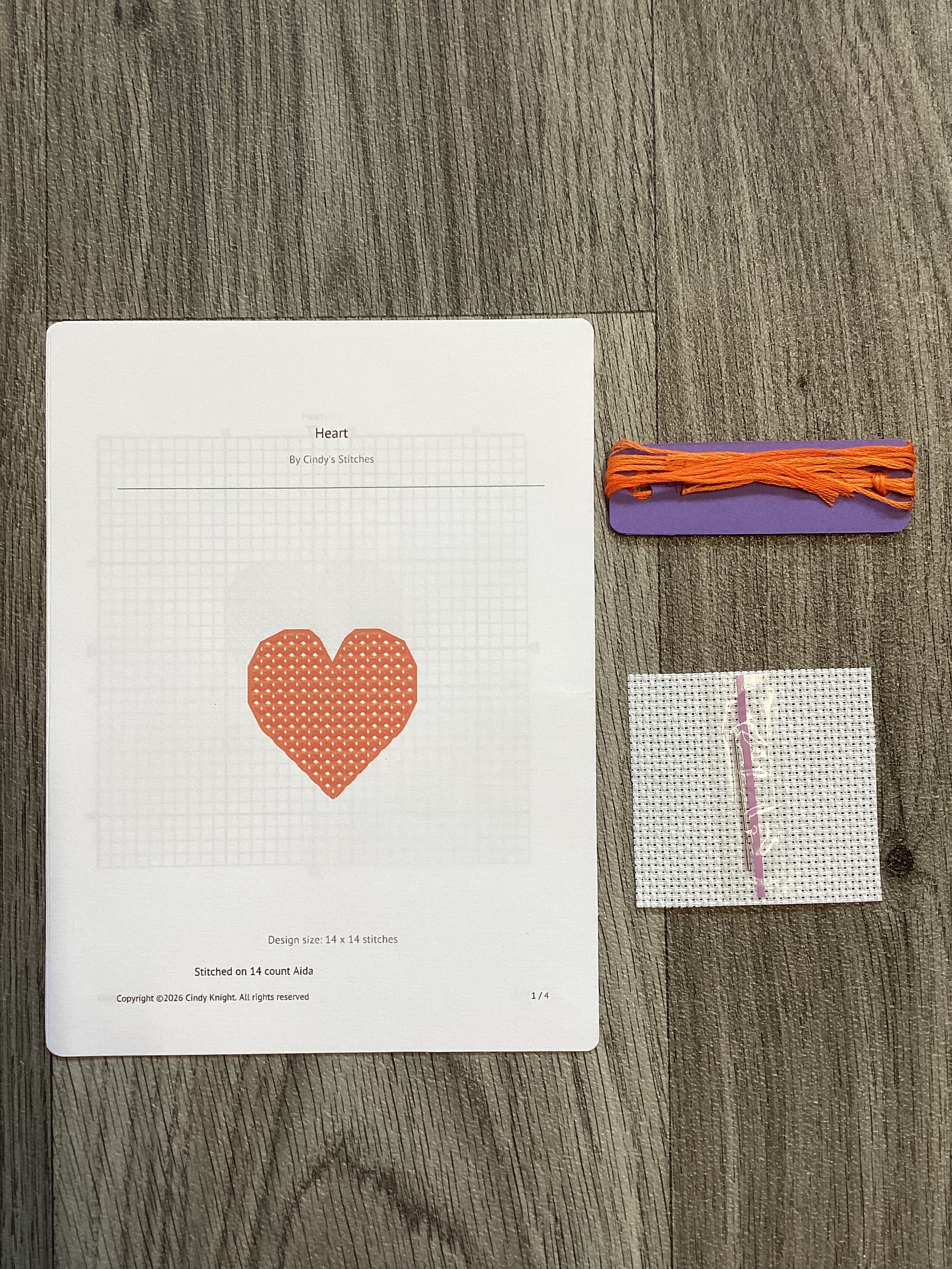 Cross stitch kit with heart pattern, orange thread, and canvas