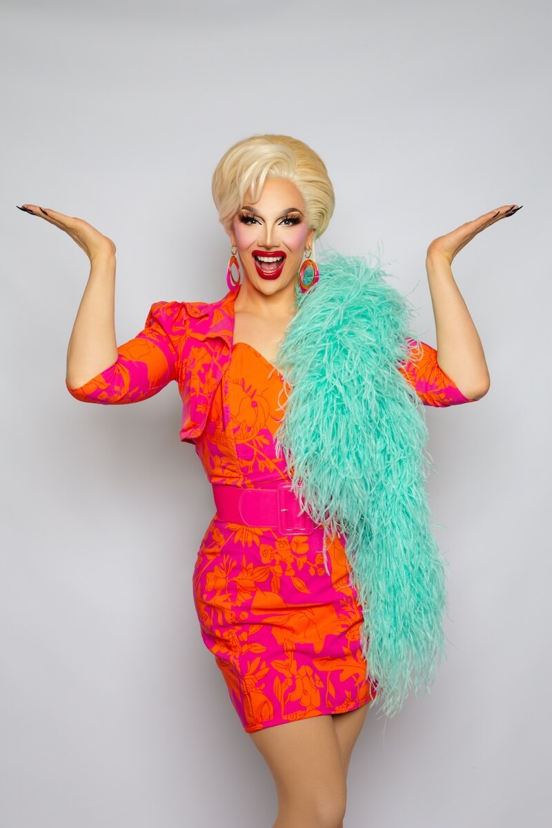 Bettie Blackheart in a bright floral dress with a turquoise feather boa