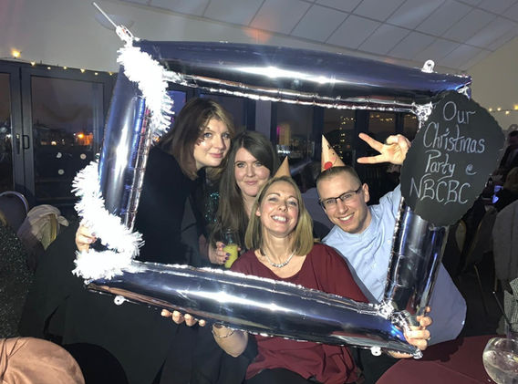 Image shows people having fun at the Christmas Party with a decorated photo frame