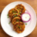 golden brown fried panko crusted zucchini fritters on a white plate with chopped scallions