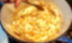 Onions are being sautéed in a blue pot, stirred with a wooden spoon. The onions are lightly browned, creating a warm, rustic mood.