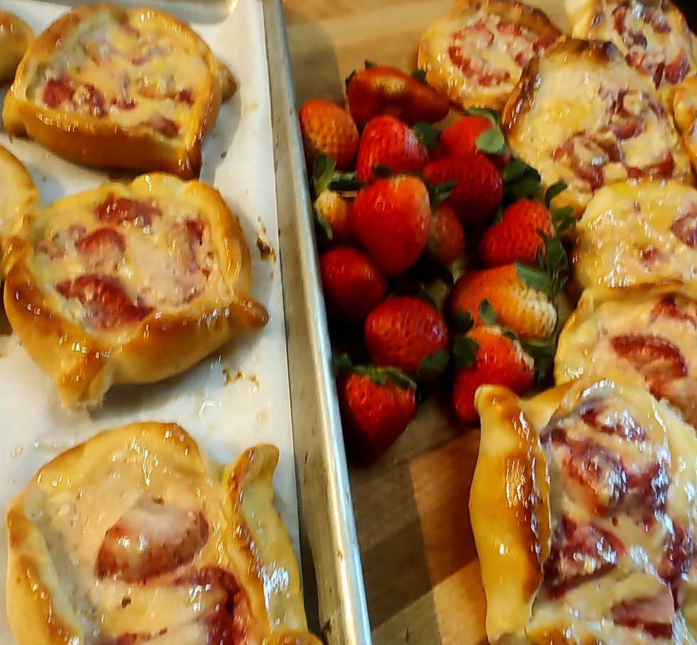 Golden pastries with strawberry filling on a baking sheet, alongside fresh strawberries on a wooden surface. Warm, inviting mood.