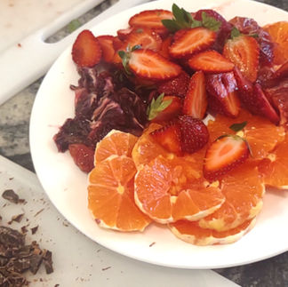 sliced strawberries, oranges on a white plate