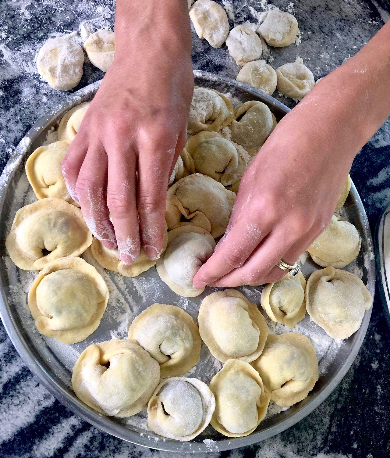 Inna putting uncooked pelmeni on a tray