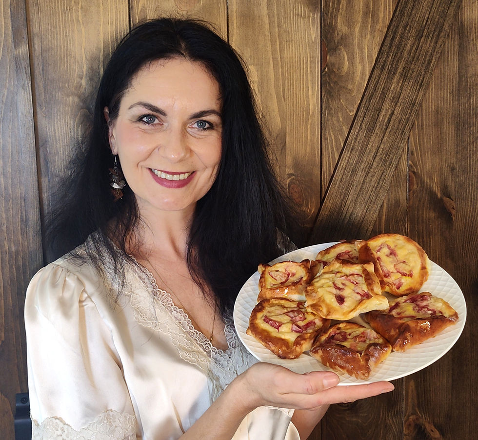 Woman in a white blouse smiling, holding a plate of pastries with a wooden background.