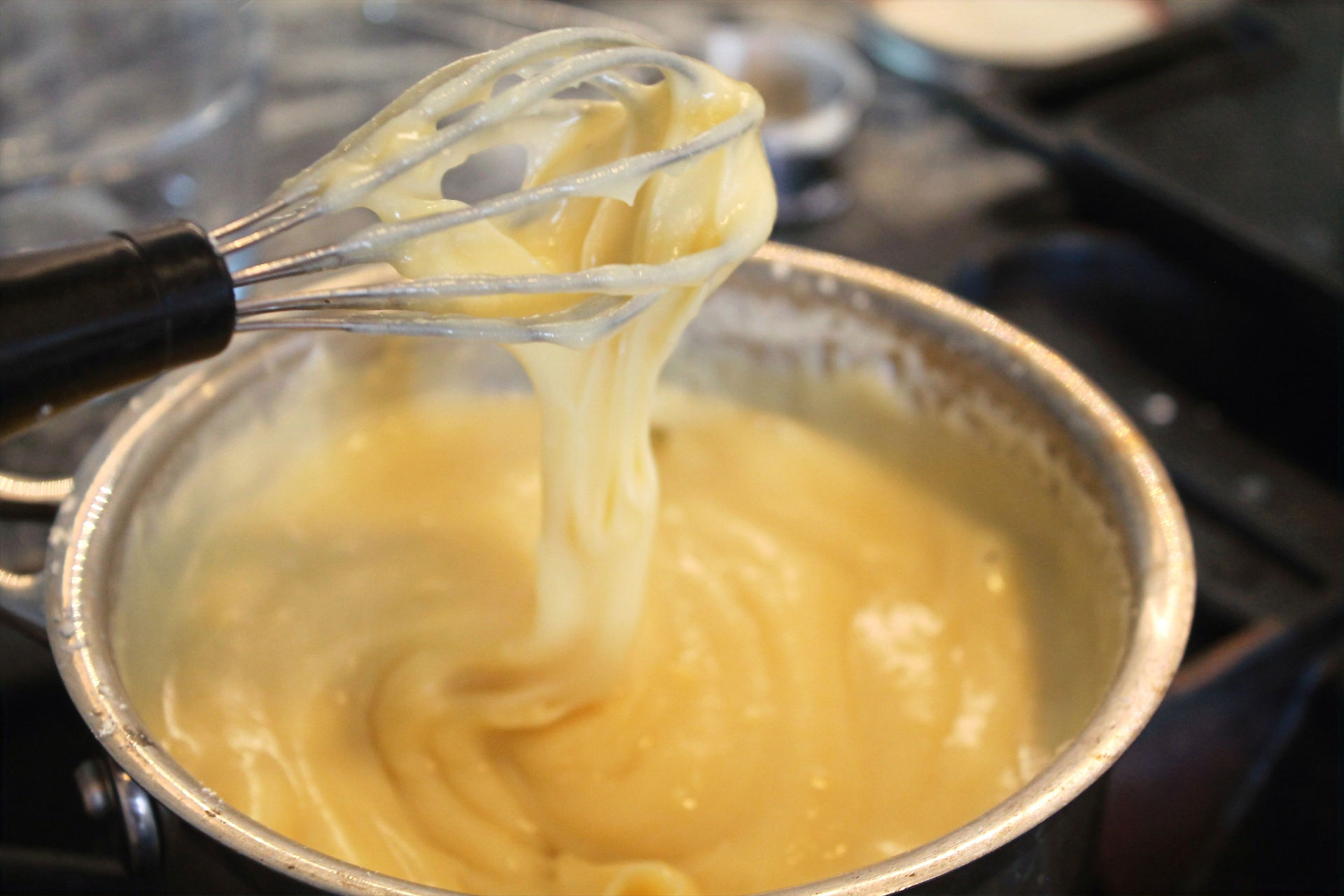 with a hand whisk checking consistency of the thick white mixture