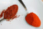red peppercorns and paprika on a spoon