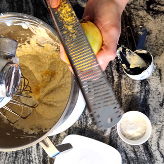 zesting lemon above the an electric mixer bowl with a cheese filling