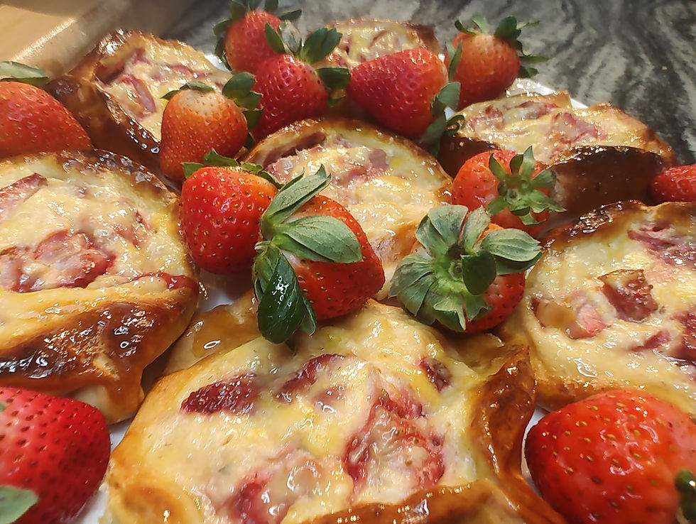 Strawberry pastries on a marble countertop garnished with fresh strawberries. The pastries are golden brown and glossy with a creamy filling.