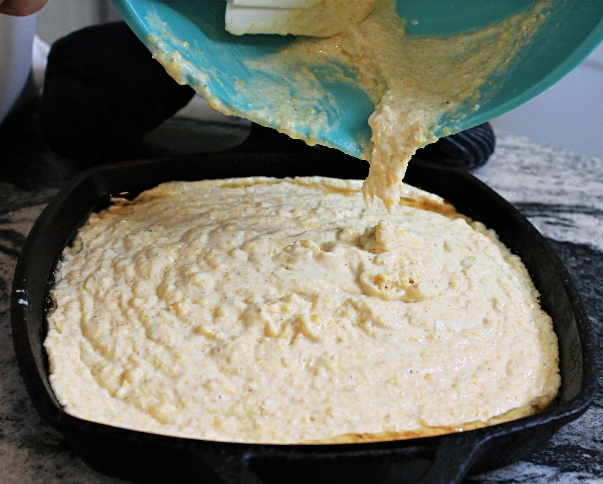 pouring cornbread batter into hot skillet