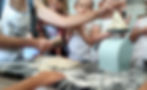 Children in aprons knead dough at a floured kitchen table; one uses a scraper, another lifts dough onto a mint mixer.