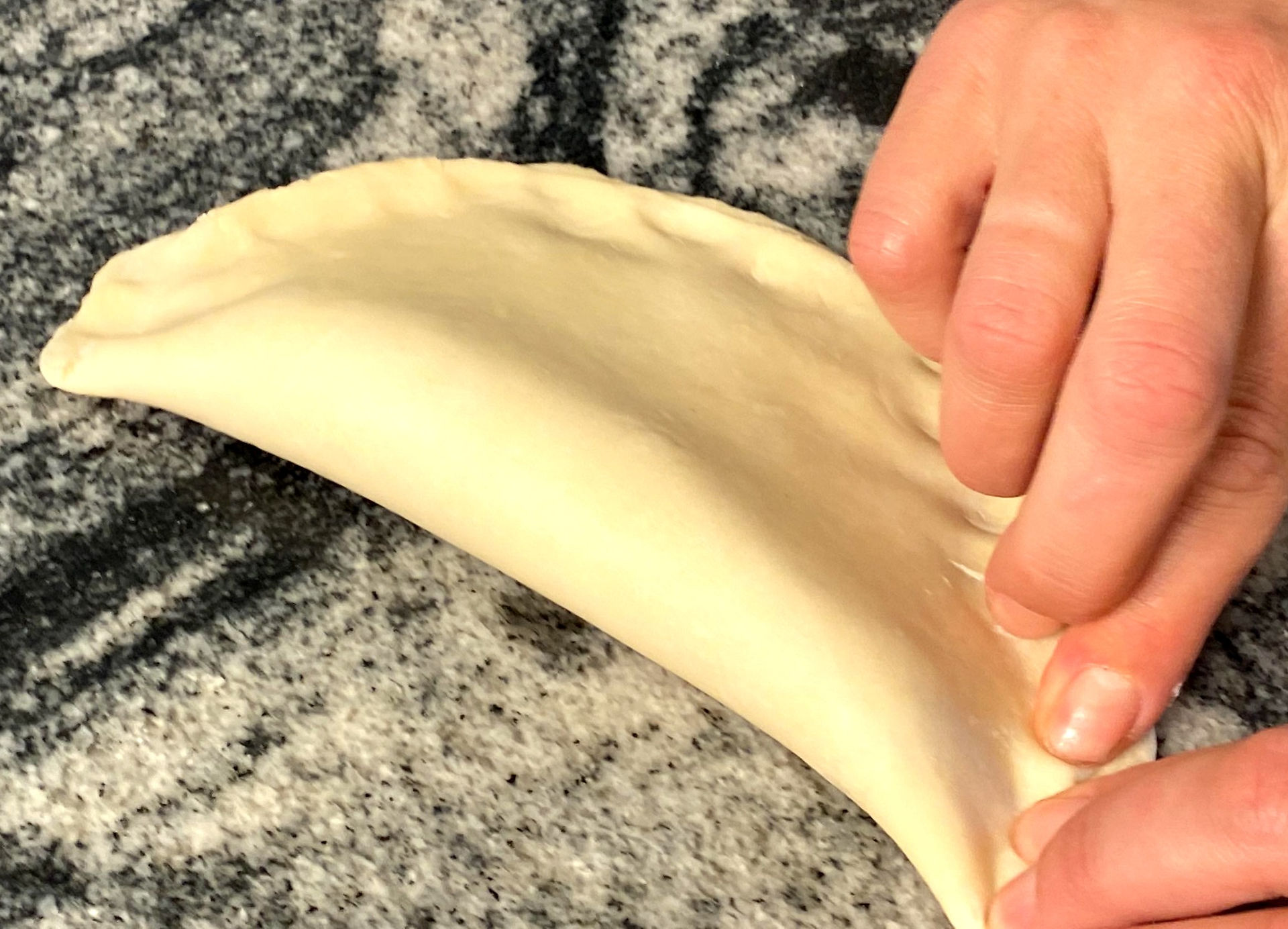 pinching a dough into a moon shape pie