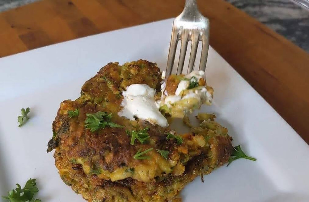 Cutting cheesy zucchini fritters with a fork