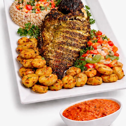 Whole grilled tilapia served with atthiéké, vegetables, and plantain.