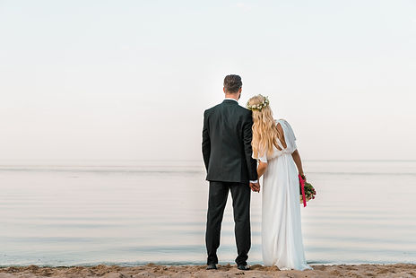 back view of wedding couple standing on beach