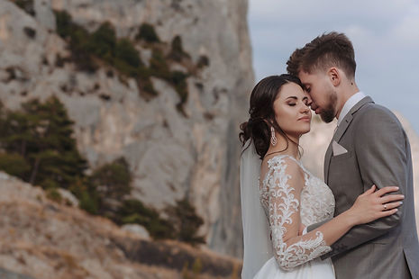 Groom holds bride in the mountains