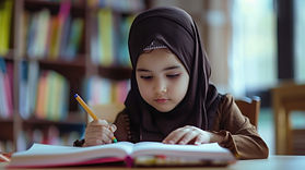 Young girl in a hijab writing in a book in a library.
