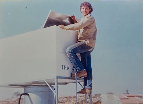 Young man climbs ladder, inspecting white "THA" labeled outdoor equipment.