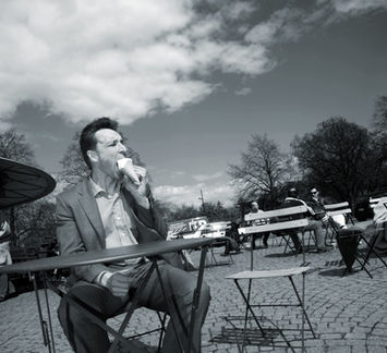 Mustavalkoisessa kuvassa mies istuu aurinkoisessa maisemassa kahvilapöydän ääressä ja syö jäätelöä. Asiakas Bisnes.fi.