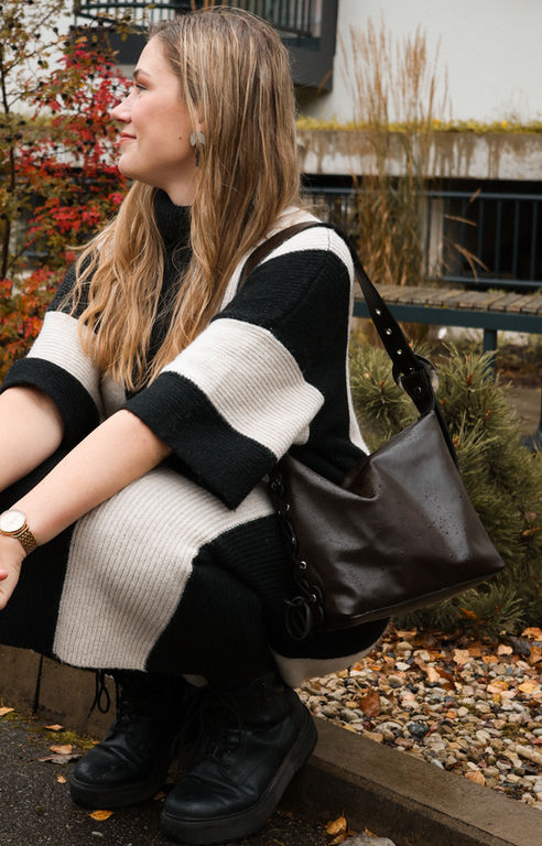 Naine mustvalges kleidis, mida kaunistab N-20 Studio šokolaadipruun õietolmukott