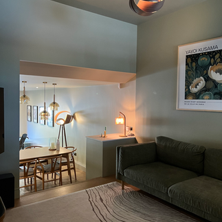 A living room with dark green sofa and light grey-green walls