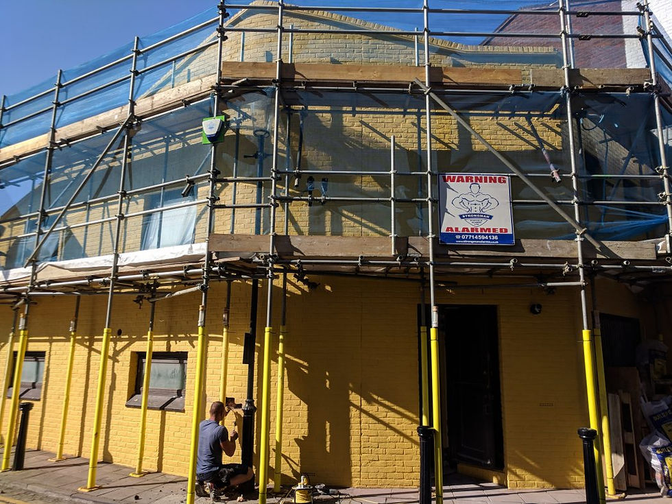 House with yellow painted bricks, surrounded with scaffolding