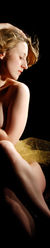 Artistic boudoir silhouette shot Ottawa Ontario gold cloth wrapped around the waist of the woman sitting on her right buttock tilting her hip pulling her left leg up to accentuate the curve of her calf to the buttock her left arm folded in and a triangle elbow resting on her left thigh her left hand touching her right shoulder her right arm raised up over her head holding her hair down while her head is tilted over the left shoulder looking towards the light and the air that's being blown to move her hair strong silhouette shot implied nudity