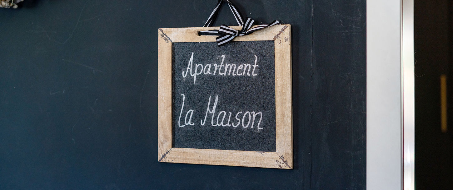 Holzschild „La Maison“ am Eingang der Ferienwohnung in Neuenkirchen