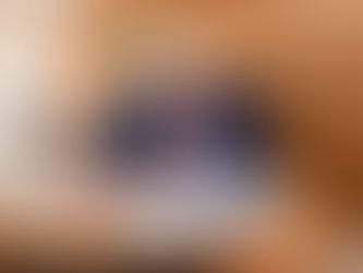 Donald Trump, in a blue suit and red tie, sits at a polished wooden desk inside what appears to be an aircraft. He is focused, holding a pen and signing a document open before him. Behind him on the wood-paneled wall, the Presidential Seal is visible. A telephone and other personal items are on the desk to his left, and a window is visible in the background. Sources