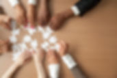 Hands of multi-ethnic team assembling jigsaw puzzle, multiracial group of black and white