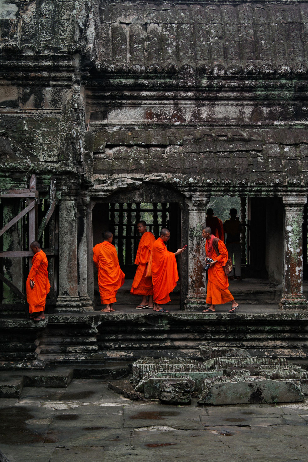 A group of monks dressed in orange walking in Angkor Wat