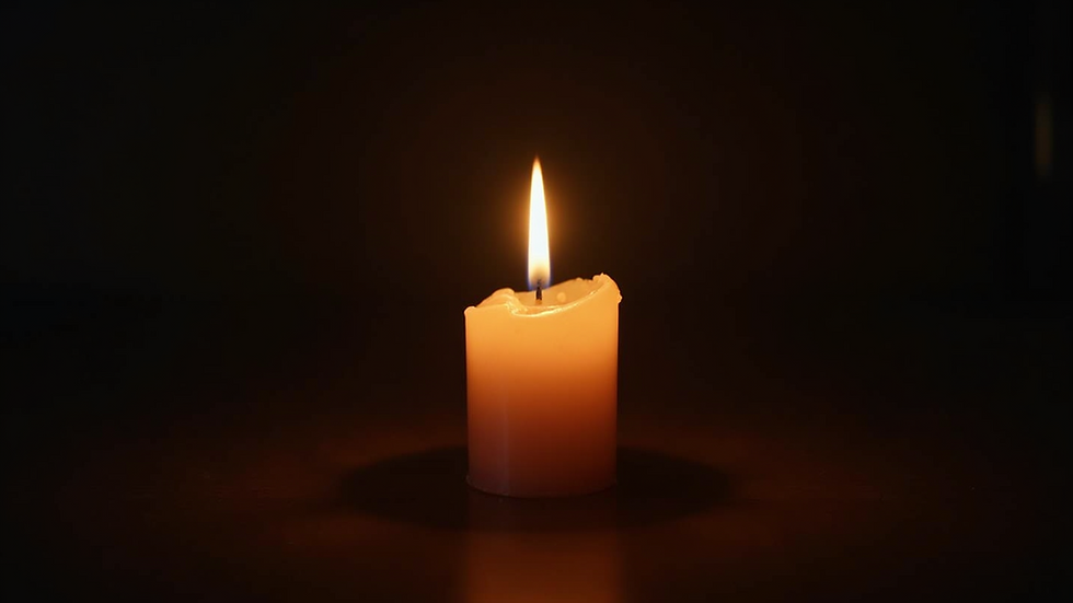 Eye level view of a glowing candle illuminating a dark room