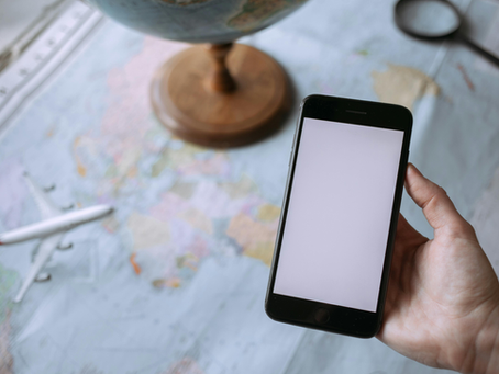Someone looking at a phone screen with a map in the background and an airplane on it