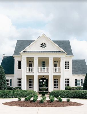 White colonial-style house with large columns, dark roof, and circular window. Donovan Manor Raleigh NC