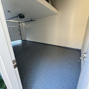 Empty garage with speckled epoxy floor and overhead shelf