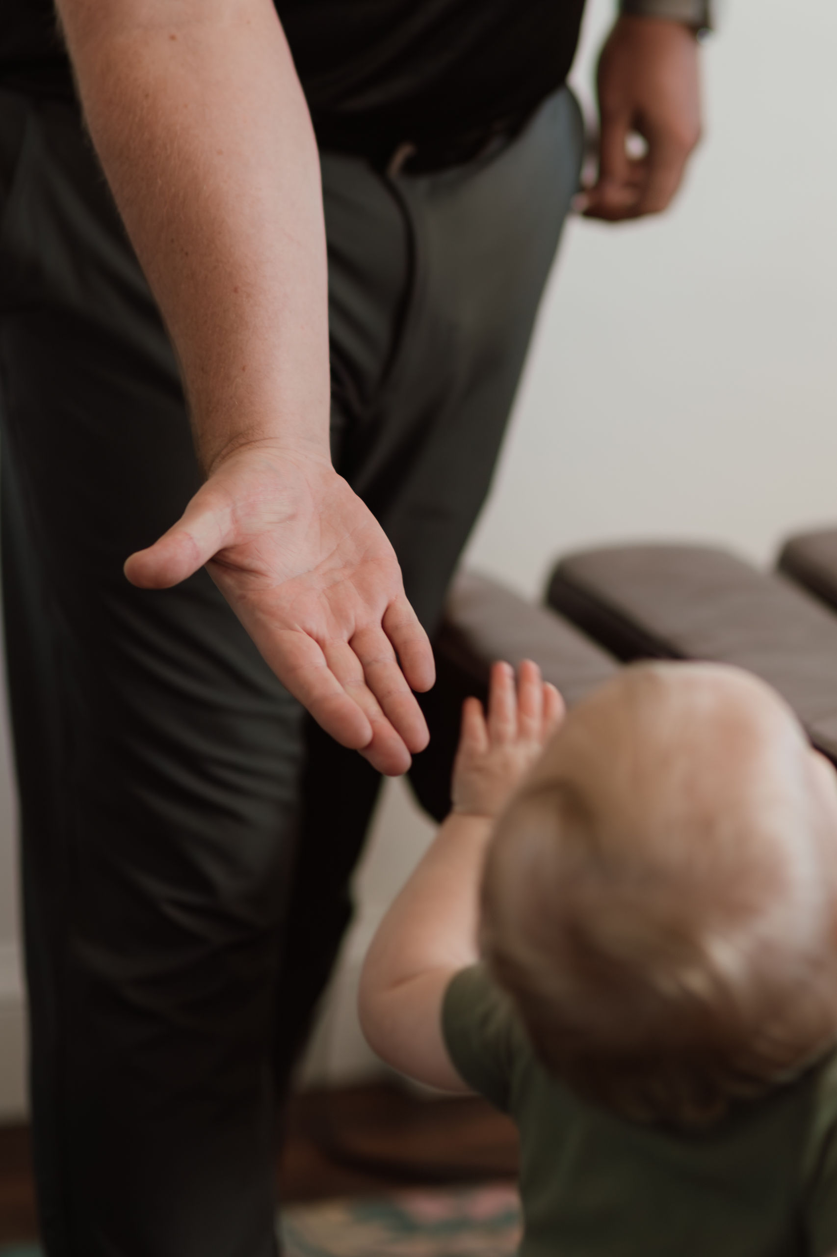 Adult reaching out to toddler, What To Expect, Holland Spine treatment.