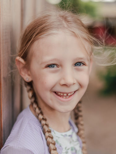 Einfühlsame Kindergartenfotografie: Ein Kind sitzt lächelnd auf einer Holzbank im Freien, Kitafotografin aus Grefrath fotografiert in Kitas in Nettetal, Viersen, Krefeld und Mönchengladbach – auch für neurodivergente Kinder.
