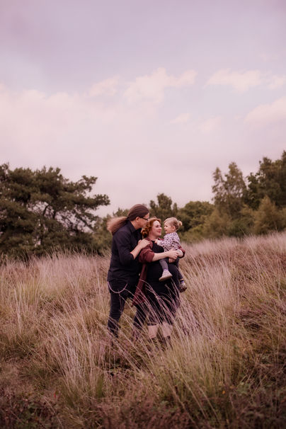Schwangere Frau im langen Kleid mit Mann und Kind beim Babybauchshooting im Sonnenuntergang in Grefrath, natürliche Schwangerschaftsfotografie Nähe Viersen.