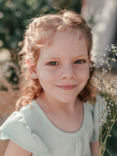 Einfühlsame Kindergartenfotografie: Ein Kind sitzt lächelnd auf einer Holzbank im Freien, Kitafotografin aus Grefrath fotografiert in Kitas in Nettetal, Viersen, Krefeld und Mönchengladbach – auch für neurodivergente Kinder.