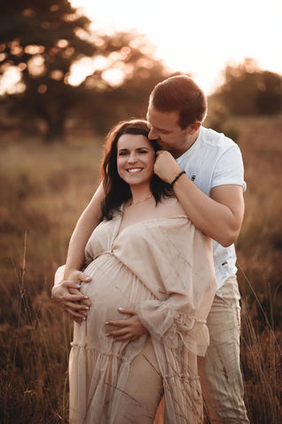 Schwangere Frau im langen Kleid mit Mann beim Babybauchshooting im Sonnenuntergang in Grefrath, natürliche Schwangerschaftsfotografie Nähe Viersen.