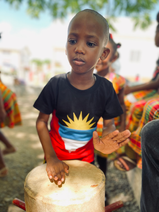 Ras Richie engaging a captivated audience of children, sharing the history of Nyahbinghi drums and the significance of African ancestry in their cultural heritage.