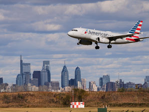 Avión de American Airlines aterrizando sobre el skyline de Filadelfia, con cielo nublado y sensación de movimiento.