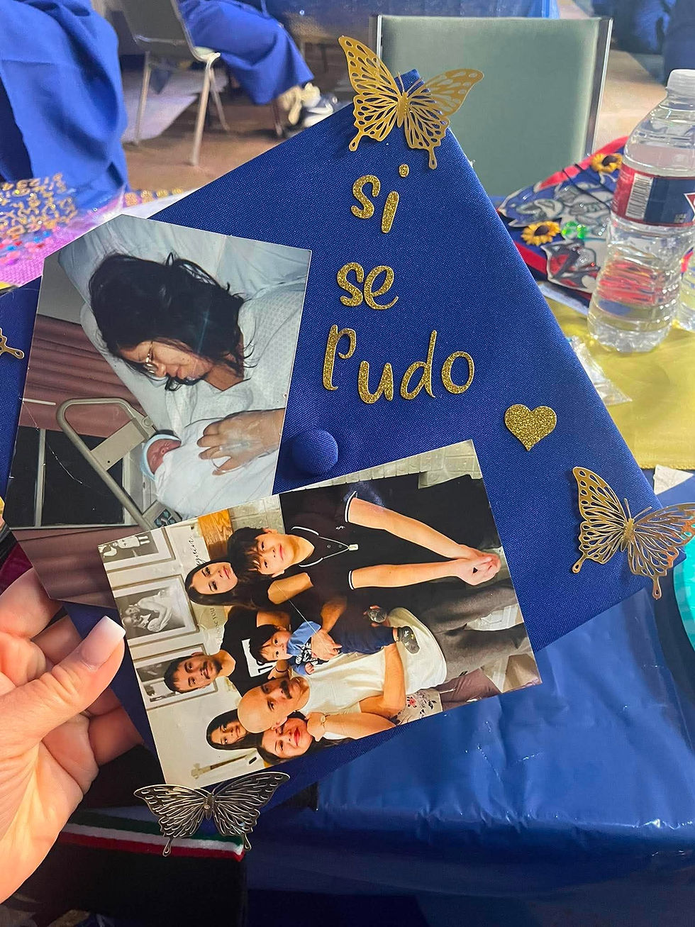 Gorro de graduación azul con mariposas doradas, fotos familiares y texto si se pudo en letras doradas.