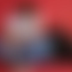 Leonel Messi baña a un bebé en una tina azul sobre fondo rojo; hay toallas, un pato de juguete y jabón, escena tierna.