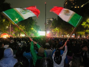 Aficionados mexicanos ondean banderas mientras observan el partido de dieciseisavos de final