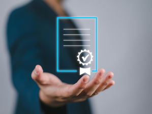 Persona con la mano extendida sosteniendo un documento digital con sello de verificación sobre fondo gris.
