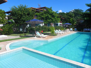 Piscina, espreguiçadeiras e guarda-sóis em um jardim
