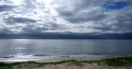Mar e praia com céu nublado e reflexo do sol