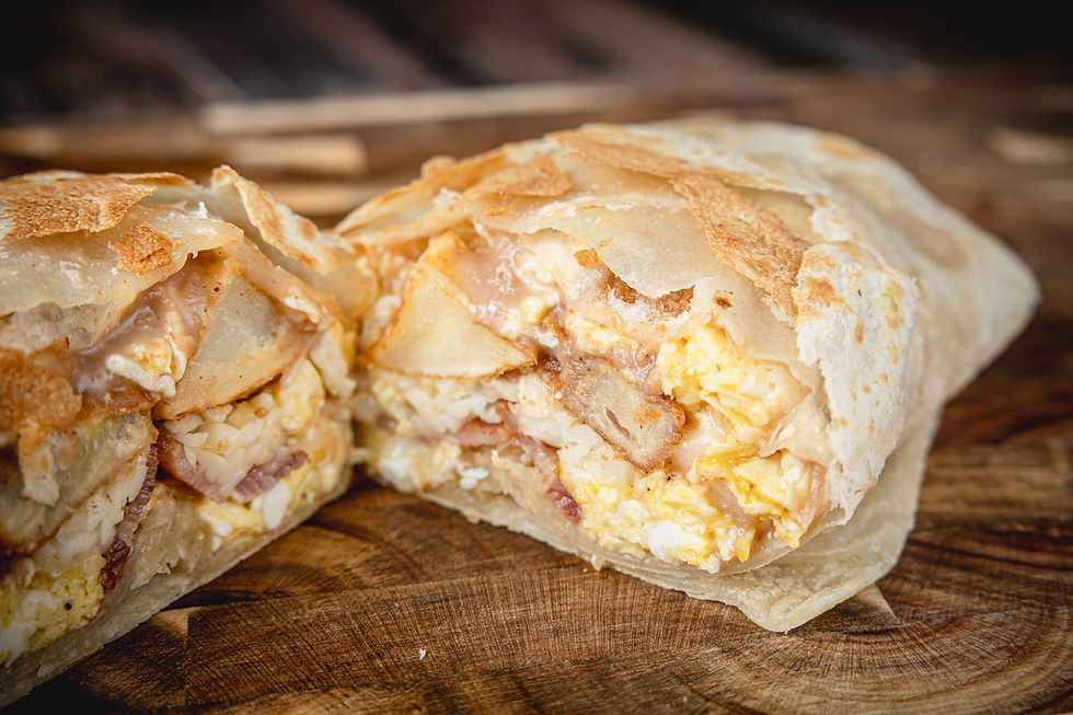 Boss Burrito from Boss Tacos cut in half showing eggs, bacon, potatoes, beans, and melted cheese