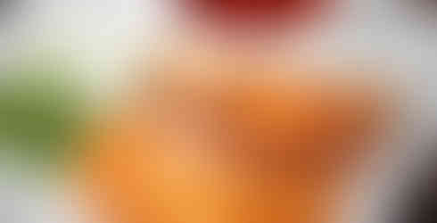 Three grilled quesabirria tacos with onions, cilantro, and consomé on the side